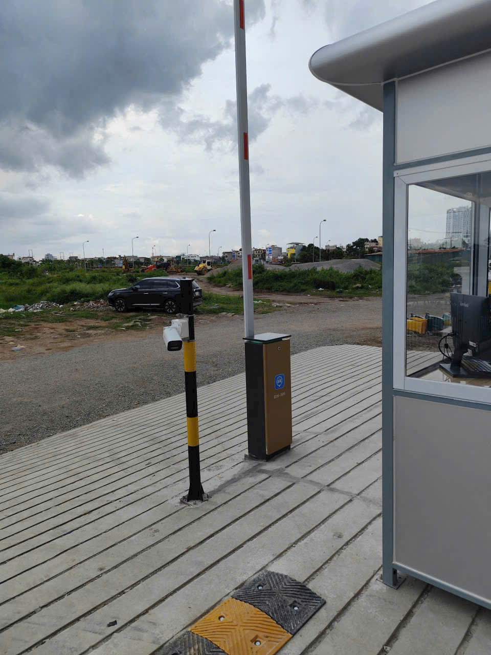 Thanh chắn barie tự động tại lối vào bãi đỗ xe ngoài trời, cạnh chòi bảo vệ và cột quét thẻ